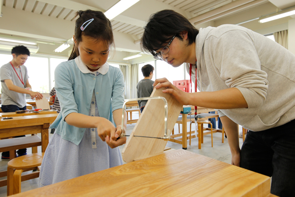 建築デザイン学科では、木工教室を開催。はじめての糸のこぎりに苦戦しつつも、学生の指導を受けながら、ミニメッセージボードを完成させていました。