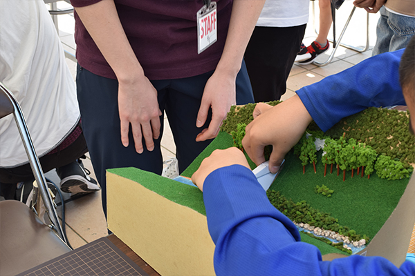 こちらはペーパークラフトで砂防ダムの模型づくり。「ここで土砂が止まるんだよ」環境土木工学科の学生が防災について子どもたちにレクチャーします。