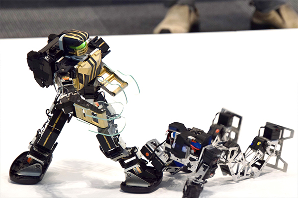 会場入口では、学生による二足歩行ロボット競技「ROBO-ONE」の実演が行われ、多くの来場者が対戦を見学されていました。