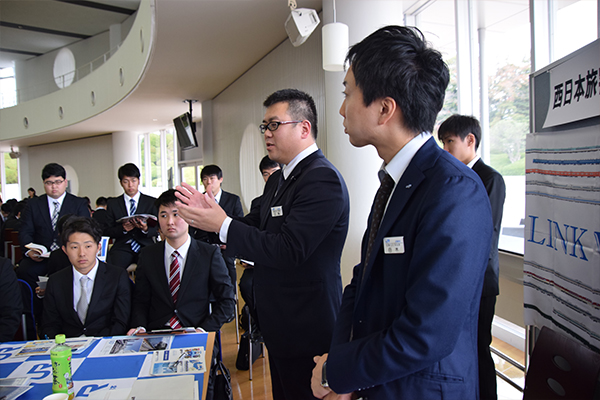 事業を説明する江角さん（奥）と白木さん（手前）。白木さんは広島工大OBで、学生たちの素朴な質問に丁寧に答えてくれました。