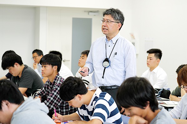 学生の間を歩いて講義する久保川先生