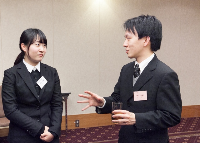 卒業生との懇親会で熱心に話を聞く坪田さん（左）