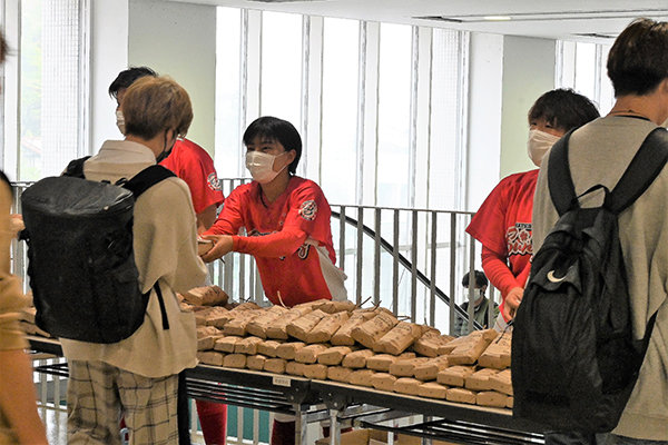 サンブレイズの選手4名が本学を訪れ、学生に直接お米を配る