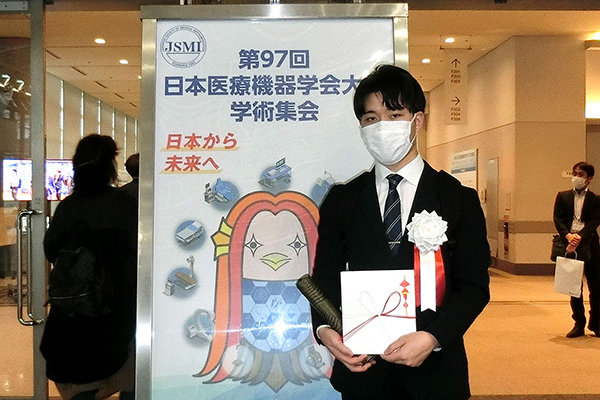 論文賞受賞の山本さん。表彰式会場のパシフィコ横浜エントランスにて