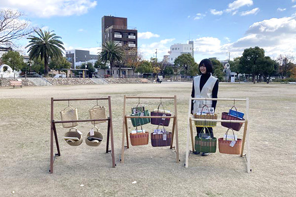 福山市の中央公園芝生広場で、デザインした本棚の説明をする釜谷さん