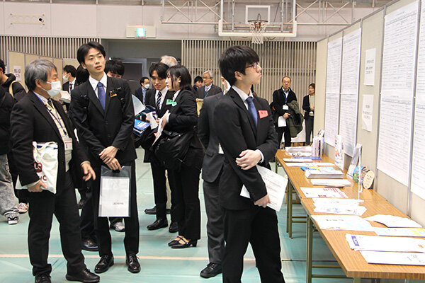 ボードに掲示された参加企業一覧を見る学生