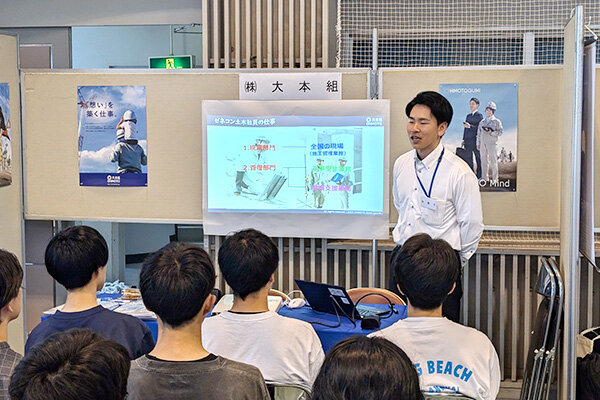 卒業生の日下さんが後輩たちに向けて会社説明を行う様子