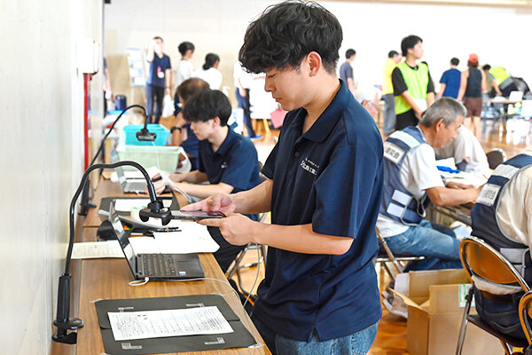 受付用紙をスマホで撮影する学生