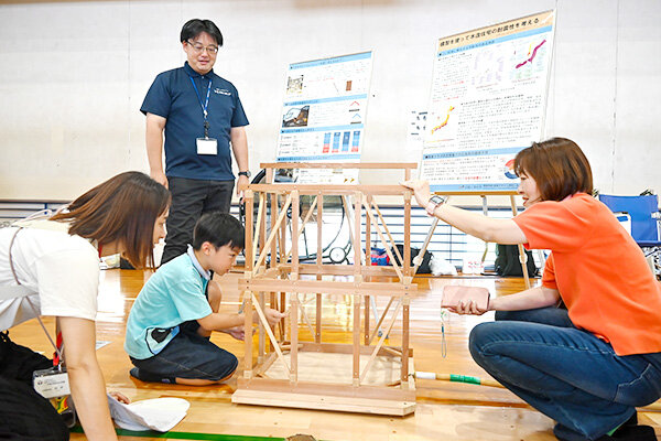 筋交いを入れ外しできる本学提供の模型で建築構造の大切さを体験する参加者