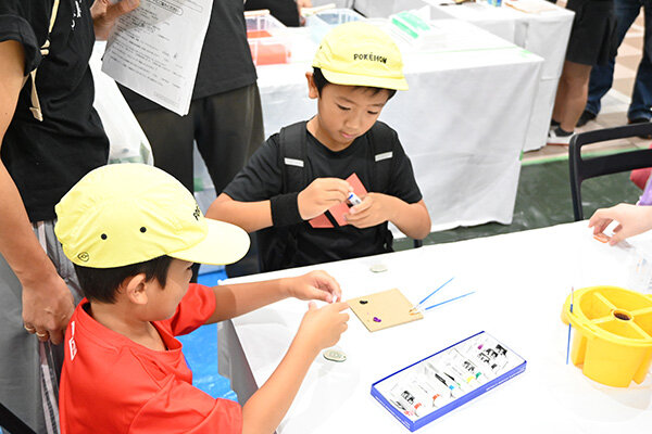 アクリル板にあらかじめ彫刻された絵柄に色を入れて仕上げるレトロキーホルダーは、年齢を問わず好評だった