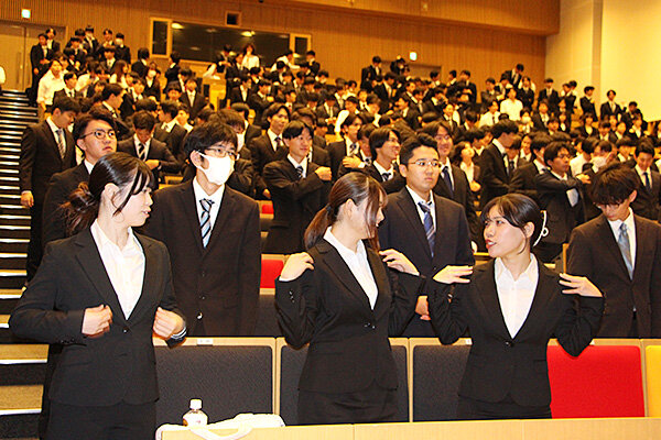 お互いのスーツの着こなしを確認し合う学生たち