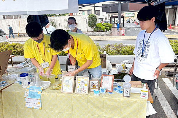 学科カラーの黄色のポロシャツを着用し、レモネードを販売する学生たち