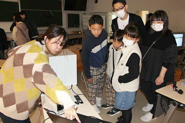 来場者に人形が動く仕組みを説明する学生