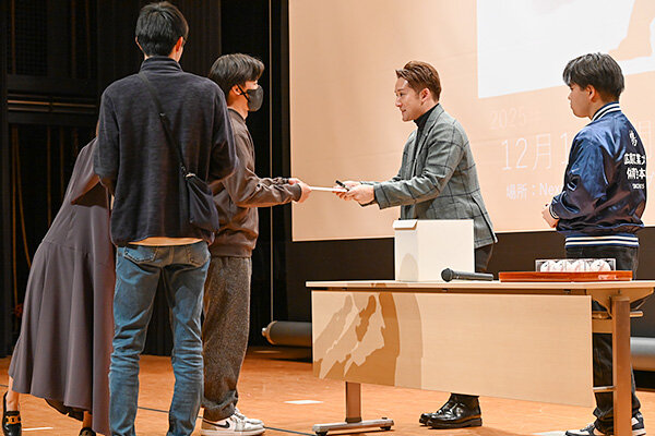 宛名入りのサイン色紙を、当選者の目を見て直接手渡す杉谷さん