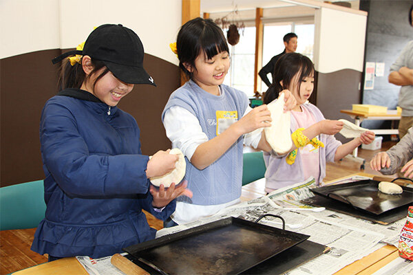 ピザ生地を手で丁寧に広げていく