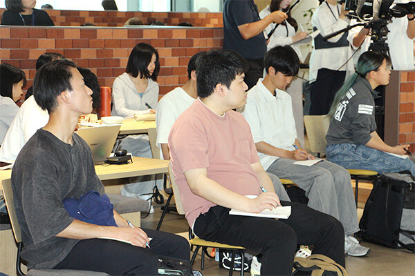 メモを取りながら真剣に話を聞く学生