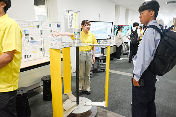 潮流発電機とおさかな牧場の研究について説明する学生