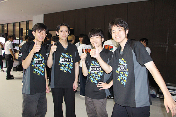 初の決勝トーナメント進出を果たし、笑顔で記念撮影する学生たち