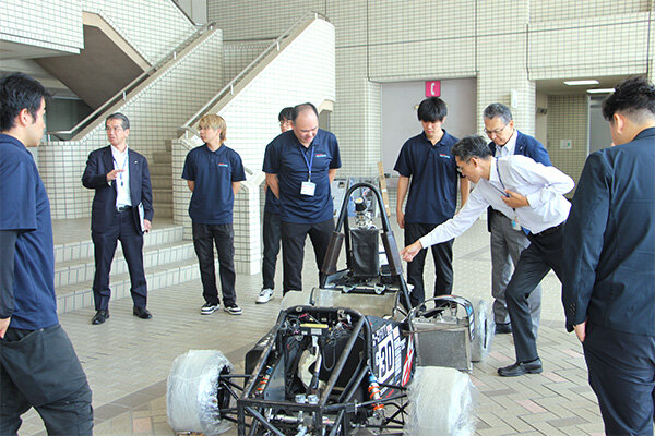 大会車両を囲みながら、開発の工夫や技術的な特徴について学生が説明した