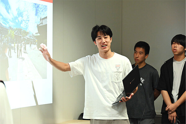 ポスターセッションで身振りを交えながら説明する学生