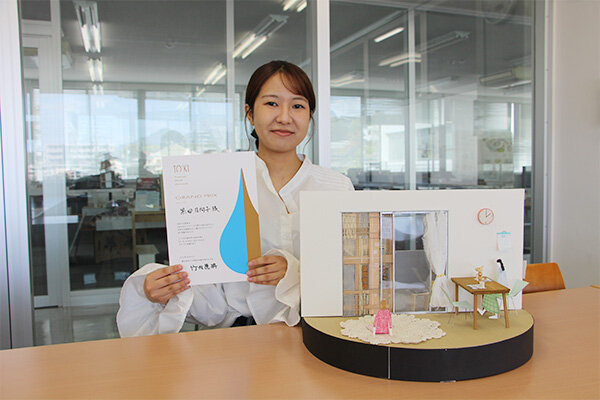 プレゼンに使用した模型を前に、表彰状を手にする黒田さん